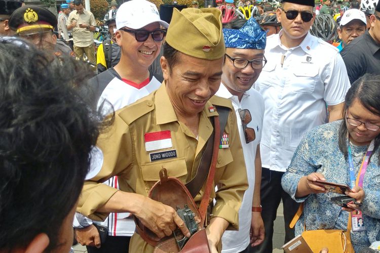 Presiden Joko Widodo mengenakan pakaian ala Bung Tomo saat bersepeda di depan Gedung Sate yang juga kantor Gubernur Jawa Barat, Sabtu (10/11/2018) pagi. Jokowi lalu memamerkan pistol mainan yang disimpan ditasnya.(KOMPAS.com/Ihsanuddin)