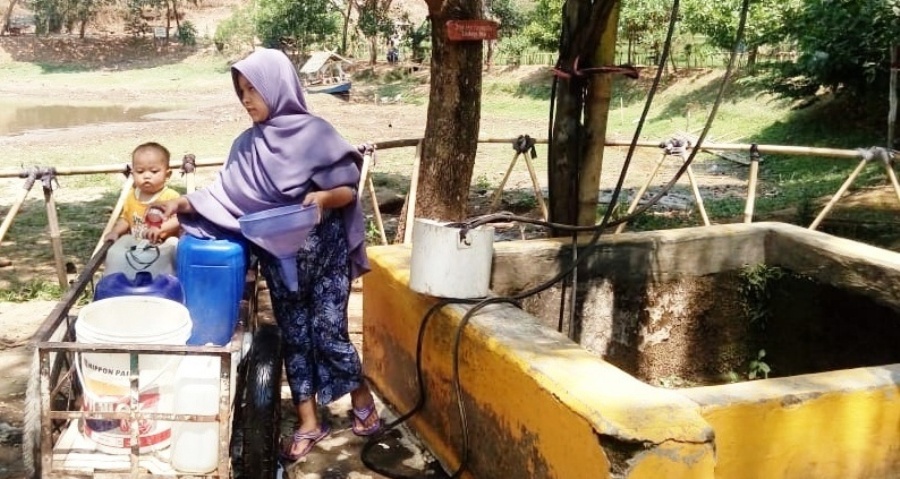 Seorang ibu bersama anaknya yang masih kecil memanfaatkan air sumur di tepian Situ Sipatahunan, Kecamatan Baleendah, Kabupaten Bandung, Jawa Barat. Air yang kurang bening itu untuk memenuhi kebutuhan sehari-hari karena air di rumahnya mulai surut dampak dari musim kemarau. Foto: dara.co.id/Muhammad Zein 