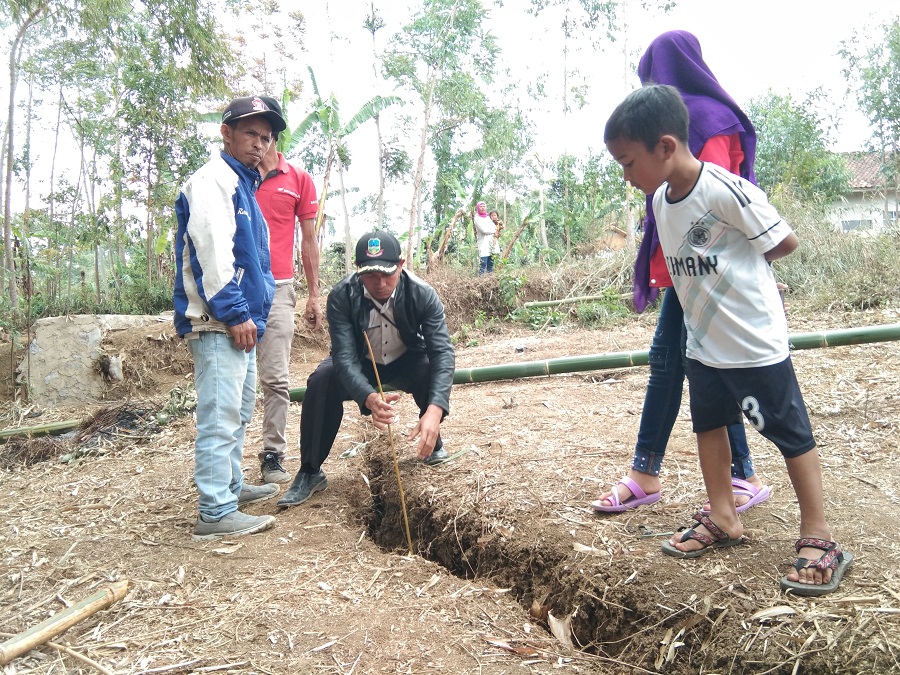 Sejumlah warga memeriksa kedalaman retakan tanah menggunakan batang bambu di Kampung Sukasari, Desa Mekarsari, Kecamatan Cikajang, Rabu (30/10/2019). Foto: dara.co.id/Beni