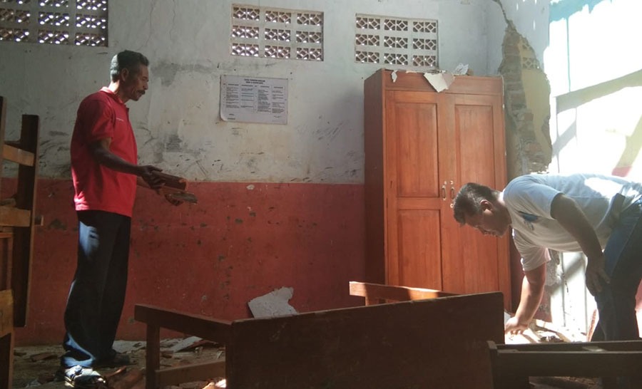 Masyarakat Desa Cijolang membersihkan sisa atap yang ambruk di ruang kelas SDN Cijolang 2, Kecamatan Limbangan, Kamis (24/10/2019). Foto: dara.co.id/Beni
