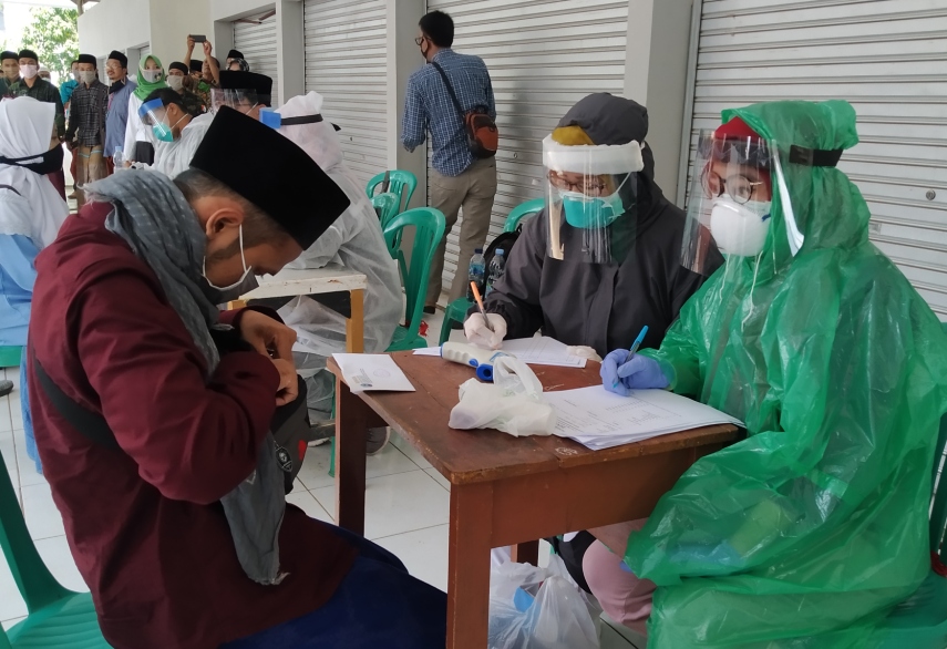 Petugas medis dari Dinas Kesehatan Kabupaten Bandung menggunakan jas hujan saat melakukan pemeriksaan kepada seorang santri di rest area Haurwangi, Kecamatan Haurwangi, Kabupaten Cianjur, Jawa Barat, Rabu (1/4/2020). (Foto: Purwanda/dara.co.id)