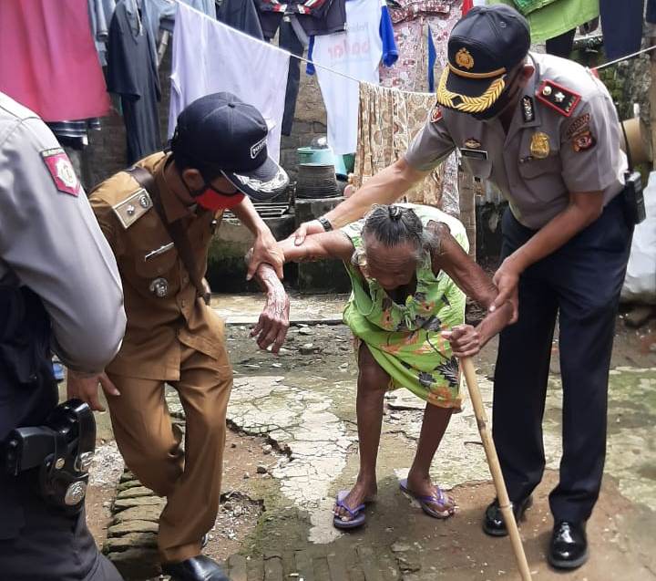 Kapolsek Katapang, Kompol Kozasah, SH M.A.P bersama Kades Banyusari H Didin Dino sedang memapah seorang jompo warga Desa banyusari (Foto: Istimewa)