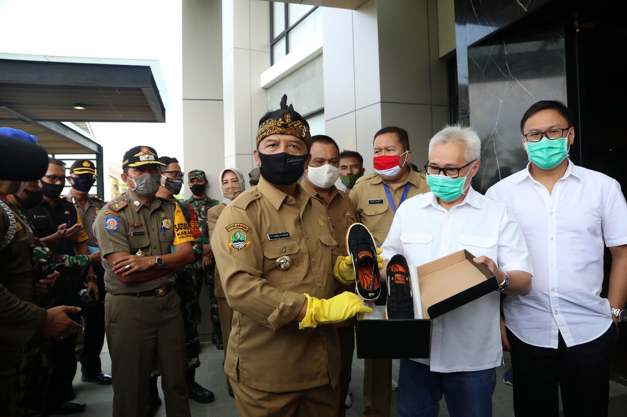 
Bupati Bandung H. Dadang M Naser memperlihat sepatu produk saat mengunjungi Pabrik PT. Sinar Runnerindo, Katapang, Kabupaten Bandung, Jawa Barat, Senin (15/6/2020). (Foto : Humas Pemkab Bandung)