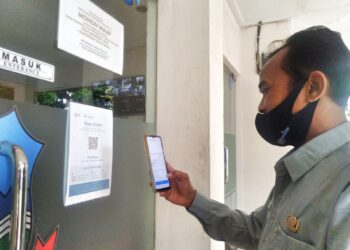 Seorang pegawai Pemkab Garut, melakukan check in masuk kantor melalui pedulilindungi (Foto: Istimewa)