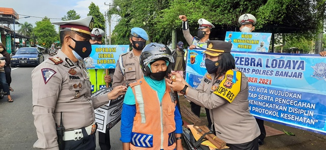 
Kapolres Banjar AKBP Ardiyaningsih saat memakaikan helm kepada pengguna jalan yang tidak memakai yang melanggar. (Foto:Bayu/dara.co.id)

