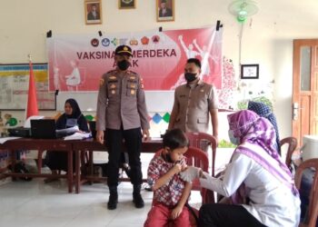 Kapolsek Semendawai Suku III IPDA Sapariyanto S.H memantau pemberian vaksi kepada siswa SD Negeri 1 Margodadi, OKU, Rabu (12/1/2022).(Foto: eko/dara.co.id)