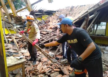 Pihak sekolah dibantu para relawan dari Pramuka tengah membersihkan matrial reruntuhan SDN Rancanilem yang ambruk pada Minggu (29/5/2022) pagi sekitar pukul 06.30 WIB. (Foto Trinata/dara.co.id).
