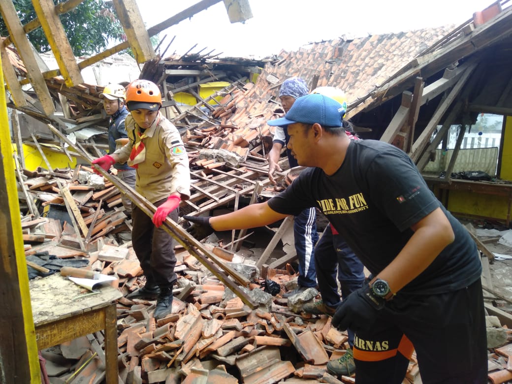 
Pihak sekolah dibantu para relawan dari Pramuka tengah membersihkan matrial reruntuhan SDN Rancanilem yang ambruk pada Minggu (29/5/2022) pagi sekitar pukul 06.30 WIB. (Foto Trinata/dara.co.id).