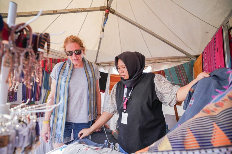 
Susie Gait turis asal Inggris tengah membeli songket khas Lombok di stan UMKM binaan Pertamina. (Foto: humas pertamina)

