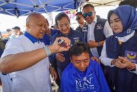 
Calon Wakil Gubernur Jabar, Ilham Habibie, mencukur rambut seorang warga saat kunjungannya ke Garut, Minggu (20/10/2024).(Foto: andre/dara)

